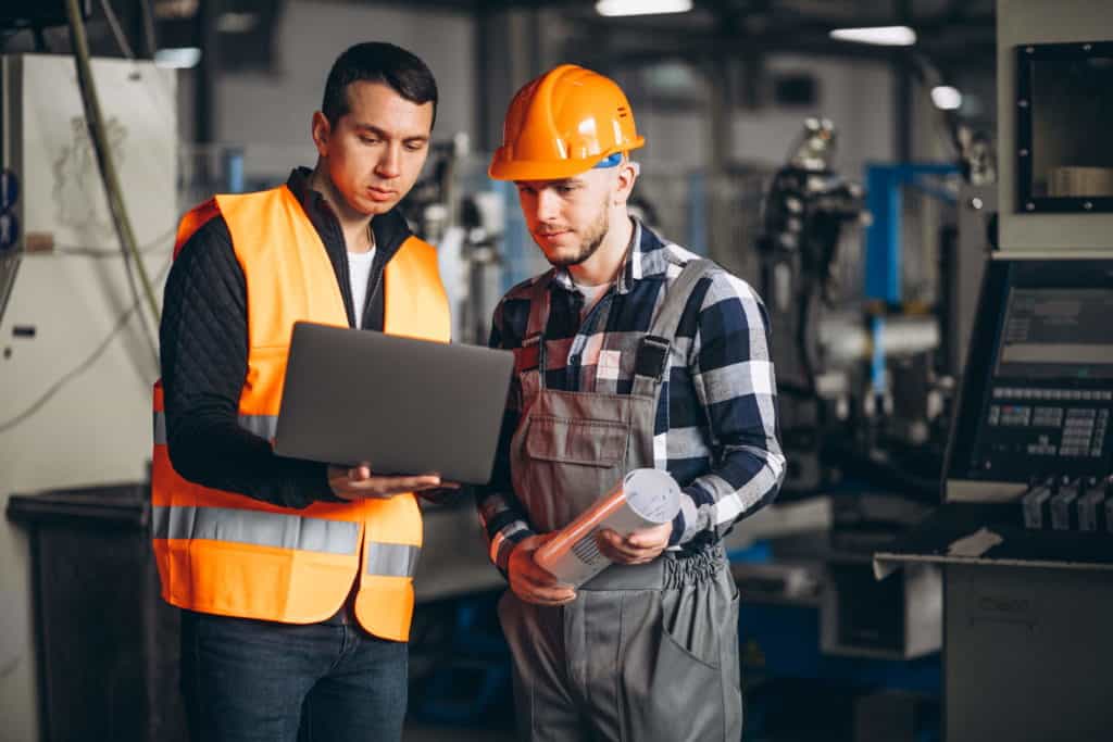 Workers reviewing Dynamics 365 Manufacturing data on a laptop