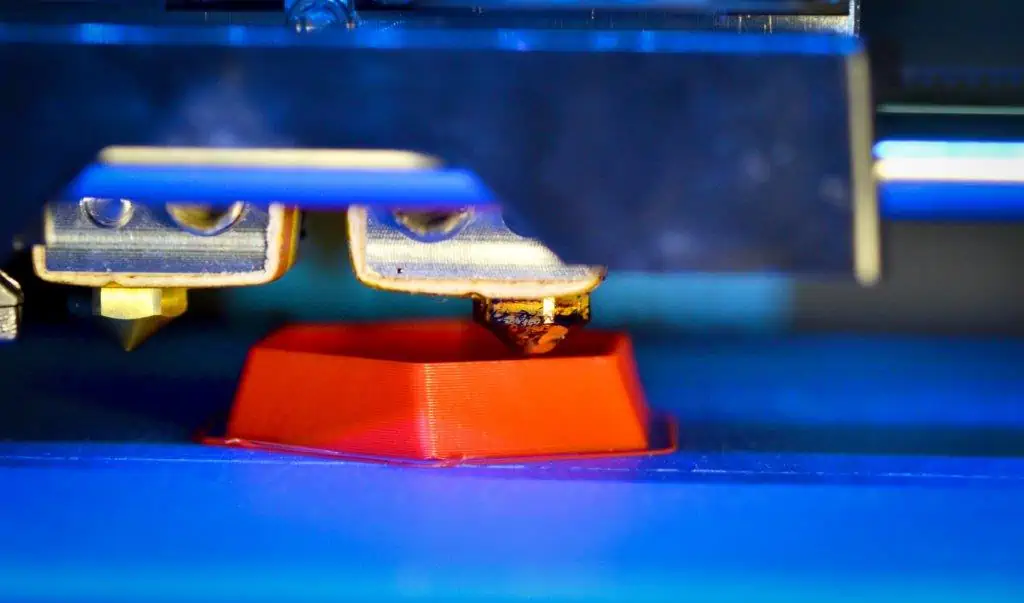 3d printer printing red faceted geometric shapes blue background close up bright contrast image automatic three dimensional 3d printer performs plastic modeling laboratory